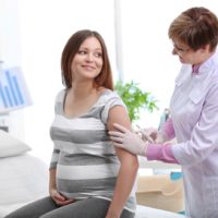 Pregnant lady being given a flu injection by the doctor